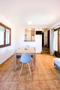 a dining room with a wooden table and blue chairs at Apartamentos Sa Cornisa in Cala Morell +14 photos
