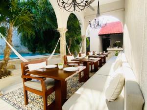 a restaurant with wooden tables and chairs and palm trees at The Diplomat Boutique Hotel in Mérida