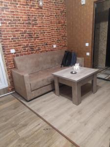 a couch and a table in front of a brick wall at COZY HOTEL SKS in Yerevan