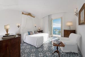 a white bedroom with a bed and a chair at Hotel Santa Caterina in Amalfi +37 photos