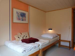 um quarto com uma cama com lençóis brancos e uma almofada vermelha em Stuga Sörgarden em Åsenhöga