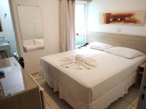 1 dormitorio con cama blanca con arco en Ellus Hotel en Dourados