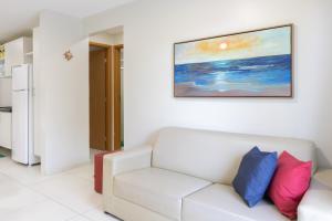 una sala de estar con un sofá blanco y una pintura en la pared en Aquarius Residence, en Porto de Galinhas