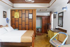 a bedroom with a bed and a desk and a table at Bamboo Bungalows in Ko Phayam