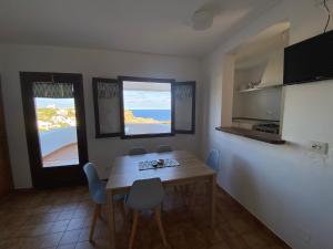 a kitchen with a wooden table and two windows at Apartamentos Sa Cornisa in Cala Morell