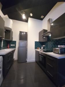 a kitchen with black and white counters and a refrigerator at L2 Apartments- City Center- 2 bed in Liverpool