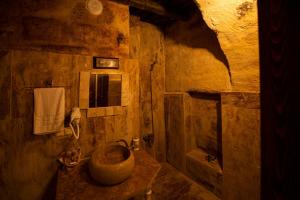 a stone bathroom with a sink and a tub at Glamada Cave Suites in Urgup
