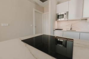 een keuken met witte kasten en een zwart aanrecht bij Apartamentos SubUp in Cabo de Palos