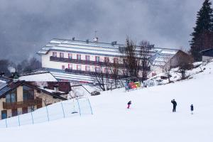 eine Gruppe von Personen, die auf einer schneebedeckten Piste Ski fahren in der Unterkunft Hotel Polsa in Brentonico