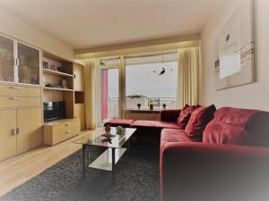 a living room with a red couch and a glass table at Berolina 519 - Ostsee Weitblick in Dahme