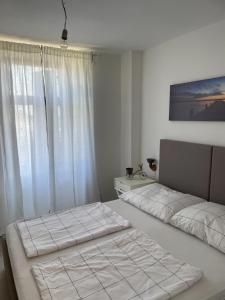 two beds in a white room with a window at Barbi Blue Apartments in Herceg-Novi