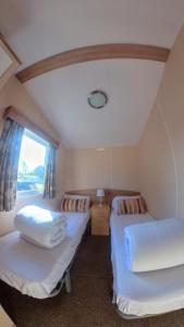 two beds in a small room with a window at Tattershall Lakes, Castle View in Tattershall