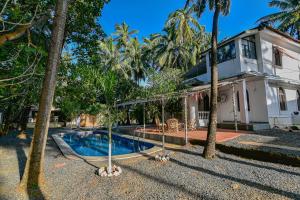 una casa con piscina y palmeras en GR STAYs Private Pool Villa in Calangute 5 mins to Baga, en Arpora