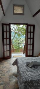 a bedroom with a bed and a large window at Pousada 2 Baioco in Paty do Alferes