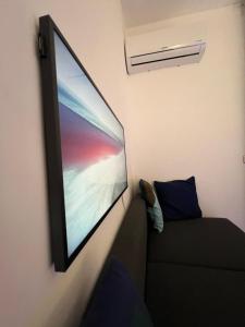 a flat screen tv hanging on a wall next to a couch at Villa Russo Apartment in Trecastagni