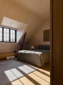 um quarto no sótão com uma cama e uma janela em Audo Copenhagen em Copenhaga