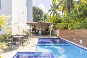 einen Pool mit einem Tisch und Stühlen neben einem Gebäude in der Unterkunft Aquarius Residence in Porto De Galinhas