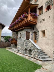 a building with a balcony with flowers on it at AL BAIT DA LUCIA Bormio in Bormio