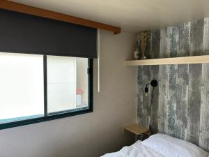 een slaapkamer met een raam en een bed met witte lakens bij Comfortabele familie chalets met veranda incl airco dichtbij zee! in Viareggio