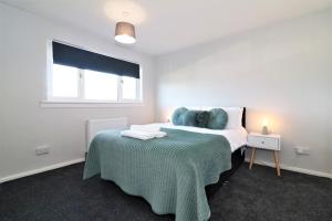 a bedroom with a bed with a blue blanket and a window at Signature - Morland House in East Kilbride