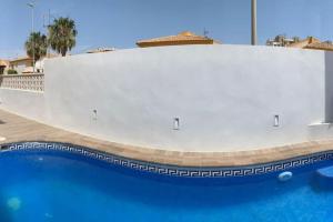 洪達海灘的住宿－Dúplex mediterráneo con piscina y cenador，游泳池旁的白色墙壁