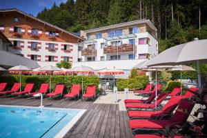 a group of chairs and umbrellas next to a swimming pool at Familotel Amiamo in Zell am See