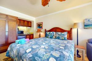 a bedroom with a bed with a blue and white comforter at Islander on the Beach 142 in Kapaa