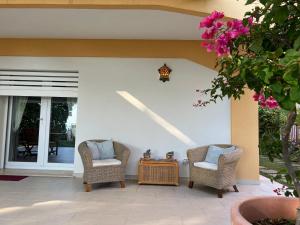 Duas cadeiras e uma mesa num pátio em Villa in front of the sea with private garden em Cittadella del Capo