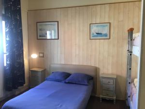 ein Schlafzimmer mit einem blauen Bett und zwei Nachttischen in der Unterkunft AUBERGE RIVA BELLA in Le Touquet-Paris-Plage