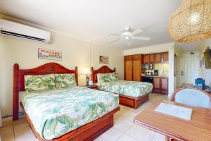 1 dormitorio con 2 camas y mesa en Islander on the Beach 111 en Kapaa