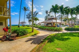 a walkway through a resort with a gazebo and palm trees at Islander on the Beach 111 in Kapaa