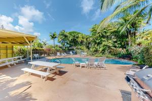 um pátio com uma mesa e cadeiras ao lado de uma piscina em Kapa'a Sands 14 em Kapaa