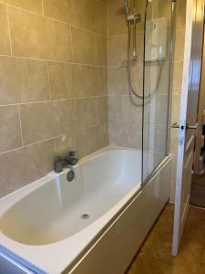 a bath tub with a shower and a sink at 3 bed house in Walsall, perfect for contractors & leisure & free parking in Walsall