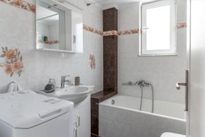 uma casa de banho branca com um lavatório, uma banheira e um espelho. em Pallas em Keratea