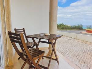 una mesa de madera y una silla en el balcón en Cosmos Retreat Baleal, en Baleal