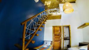Habitación con escalera de madera y pared azul. en Pousada Rosa dos Ventos Lagoinha, en Lagoinha