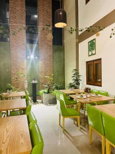 un restaurante con mesas de madera y sillas verdes en J Leaf Hotel By Blue Bird, en Negombo