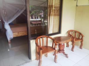 2 sillas de madera y una mesa en una habitación en Wisma Leuser Sibayak, en Bukit Lawang