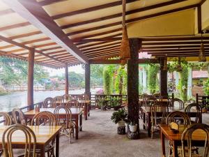 a restaurant with wooden tables and chairs and a river at Wisma Leuser Sibayak in Bukit Lawang