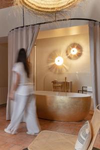 a woman walking in front of a tub in a room at MiHotel Tour Rose in Lyon
