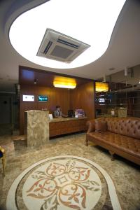 a lobby with a couch and a person at a counter at GK Regency Suites Hotel in Istanbul