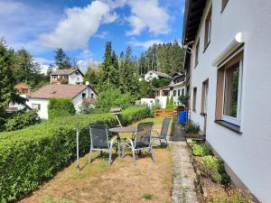 a patio with chairs and a table in a yard at FeWo mit Terrasse für 4-5 Personen mit Schwimmbad + Sauna in Bad Grund