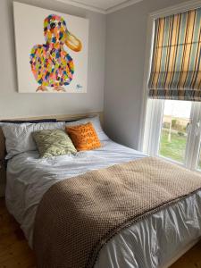 a bed in a bedroom with a painting on the wall at The Patch in Hill Head