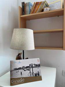 een boek op een tafel naast een lamp bij Villa Verdi Apartments in Grado