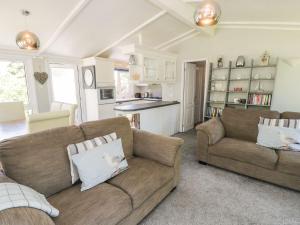 a living room with two couches and a kitchen at Orchard Lodge in Pwllheli