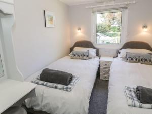 two beds in a small room with a window at Orchard Lodge in Pwllheli