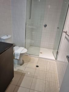 y baño con ducha y aseo. en Collins central 2-bd apartment with pre-reserve parking, en Melbourne