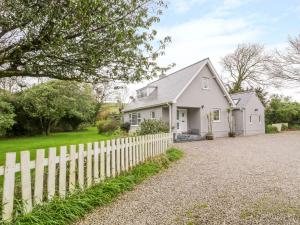 a white house with a white picket fence at The Orchard in Pwllheli