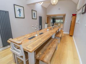 a large wooden table with benches in a room at The Orchard in Pwllheli