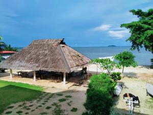 une cabane avec un toit de paille sur la plage dans l'établissement Ten RooMs, à Telukbakau